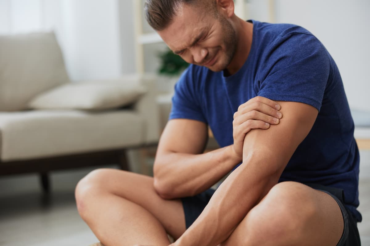 Persona agarrándose el bíceps debido a un dolor muscular