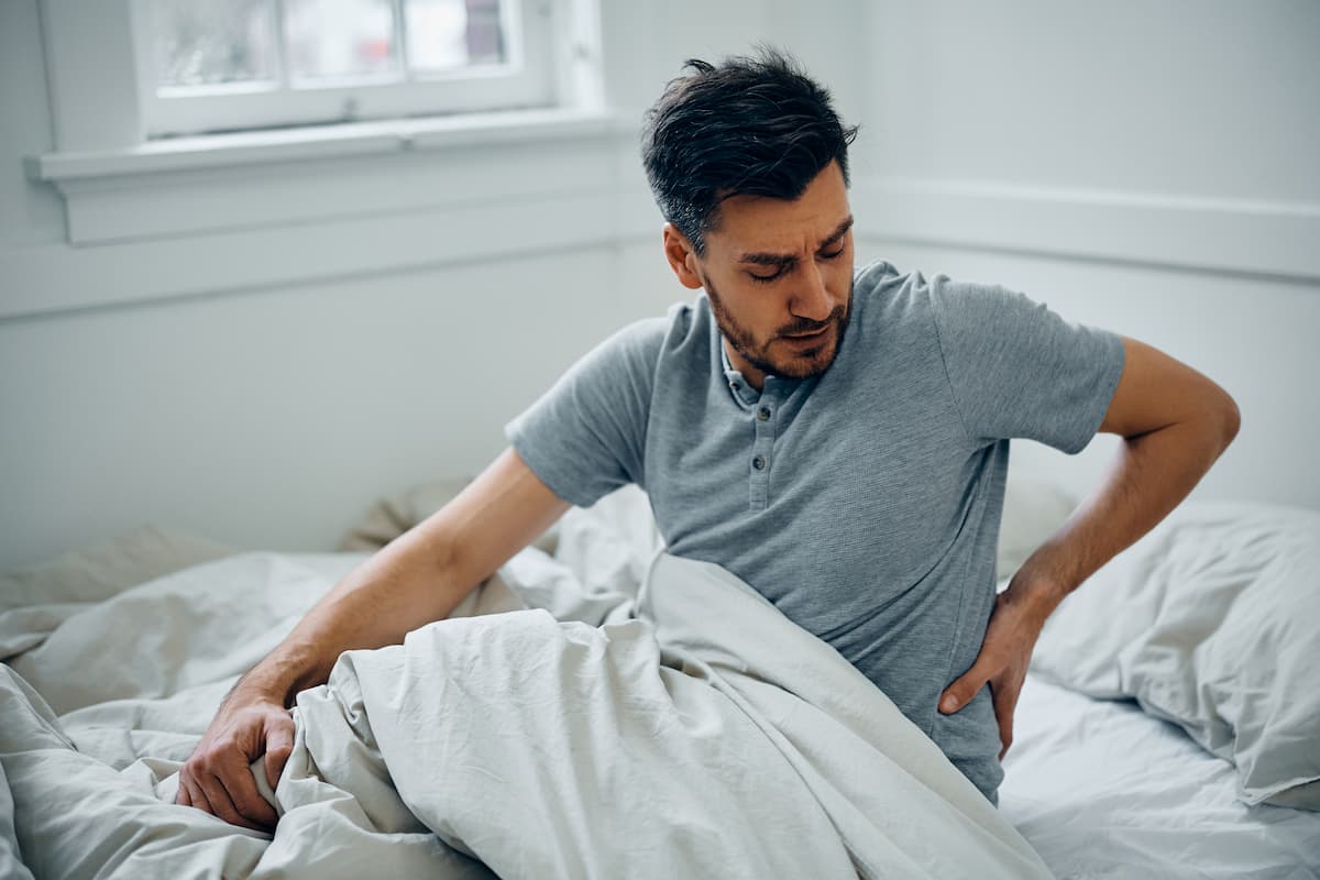 Las mejores posturas para dormir con dolor lumbar, mostrando cómo alinear la columna para aliviar la tensión en la espalda baja.